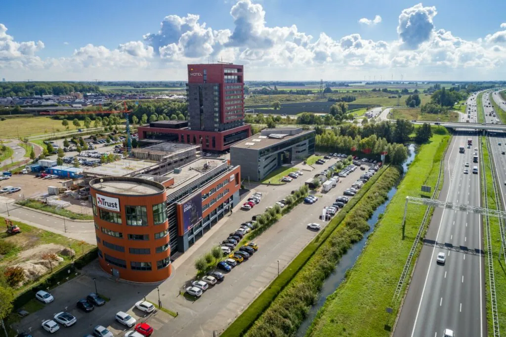 Luchtfoto van de Laan van Barcelona in Almere met kantoorgebouwen, een hotel, parkeerplaatsen en de snelweg A6.
